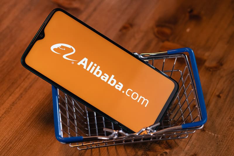 A mobile phone in a mini shopping cart showing the Alibaba.com logo